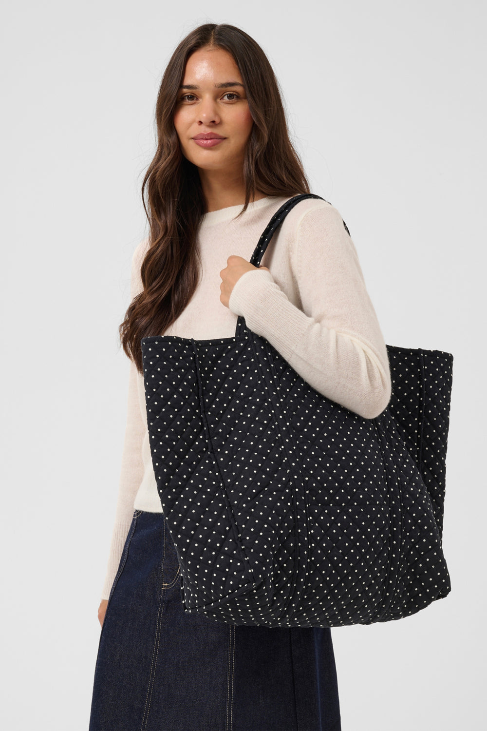 A women's black and white polka dot quilted tote bag. 