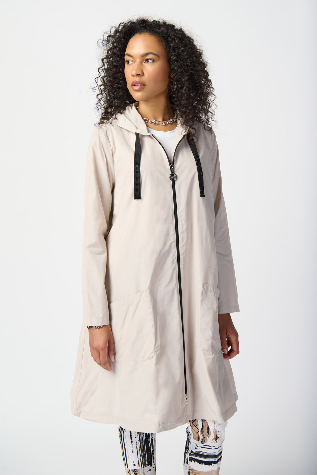 Joseph Ribkoff Spring 2024 a classic, modern and sleek design that combines fashion and function. This long coat features a drawstring hood and full front zipper for added warmth and style. 