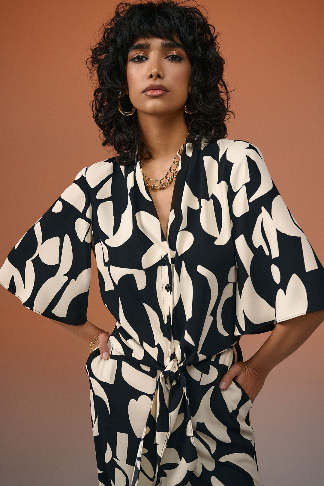 Joseph Ribkoff Summer 2024 Expertly crafted from a flowing fabric, this chic blouse features a button front with an open v-neck chest for a modern twist. 