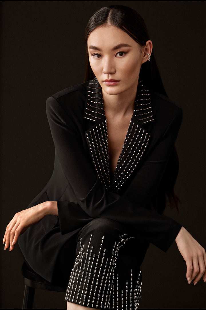 Joseph Ribkoff Fall 2024 With its stunning bling and glitz details, this blazer is a true showstopper! The single button closure adds a touch of sophistication, while the contrast bling notch collar is the main feature that sets it apart.