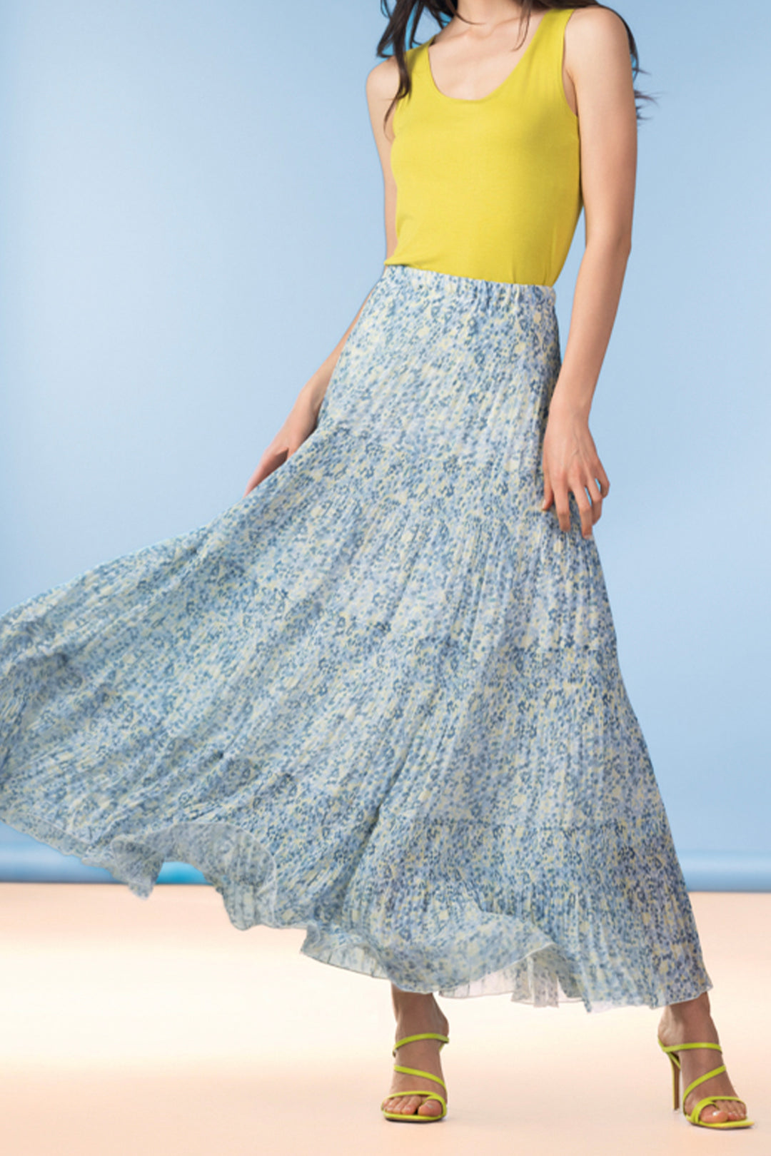 Woman wearing a long blue floral skirt against a light blue background.
