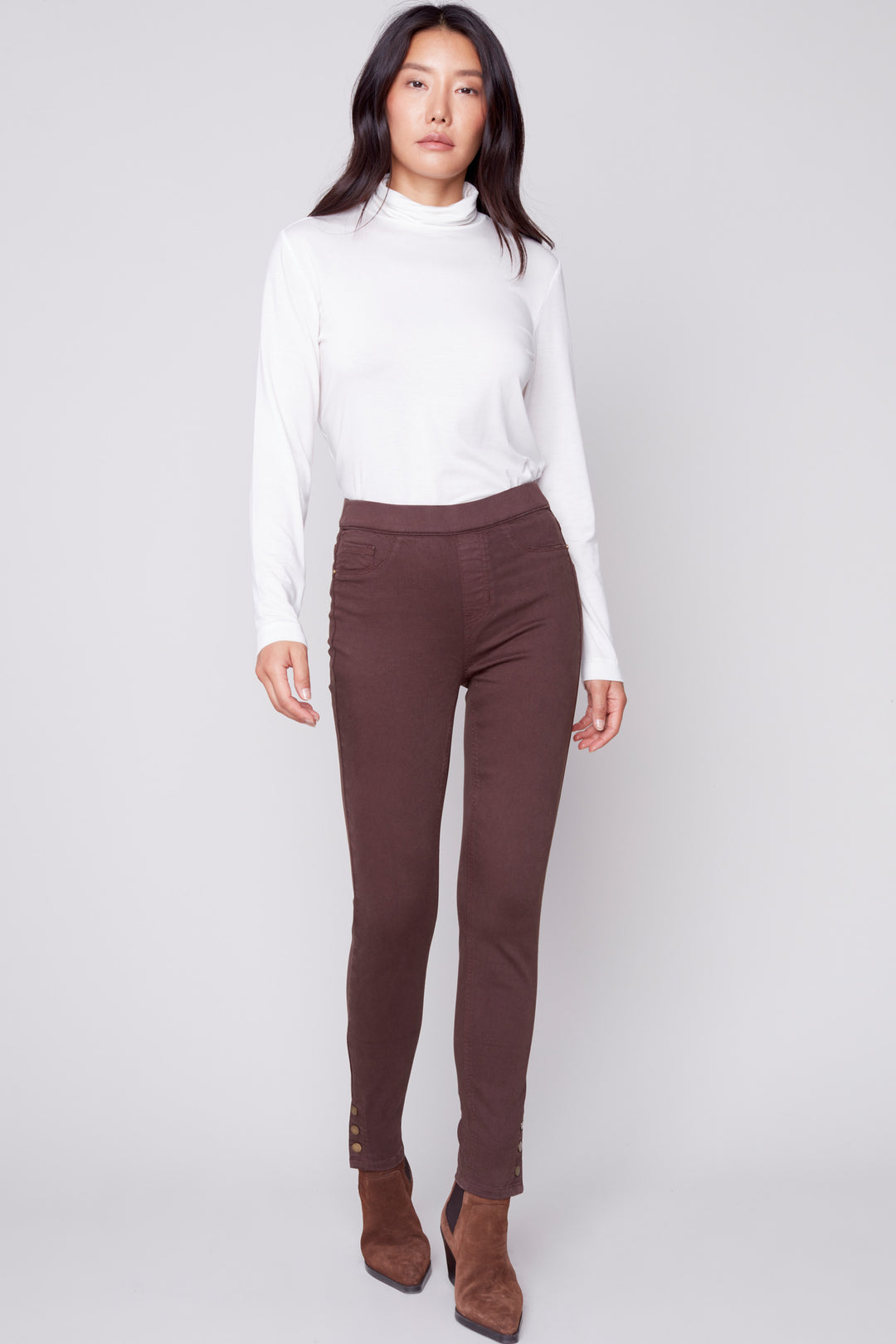 The Snap Jean is a chic pant crafted from lightweight stretch twill fabric. It features a pull-on design with a snap button hem for a polished, tailored look. The slim fit style provides a slimming silhouette and can be easily styled for a variety of occasions. Available in a chocolate colour, it’s perfect for creating a fashion-forward new look.