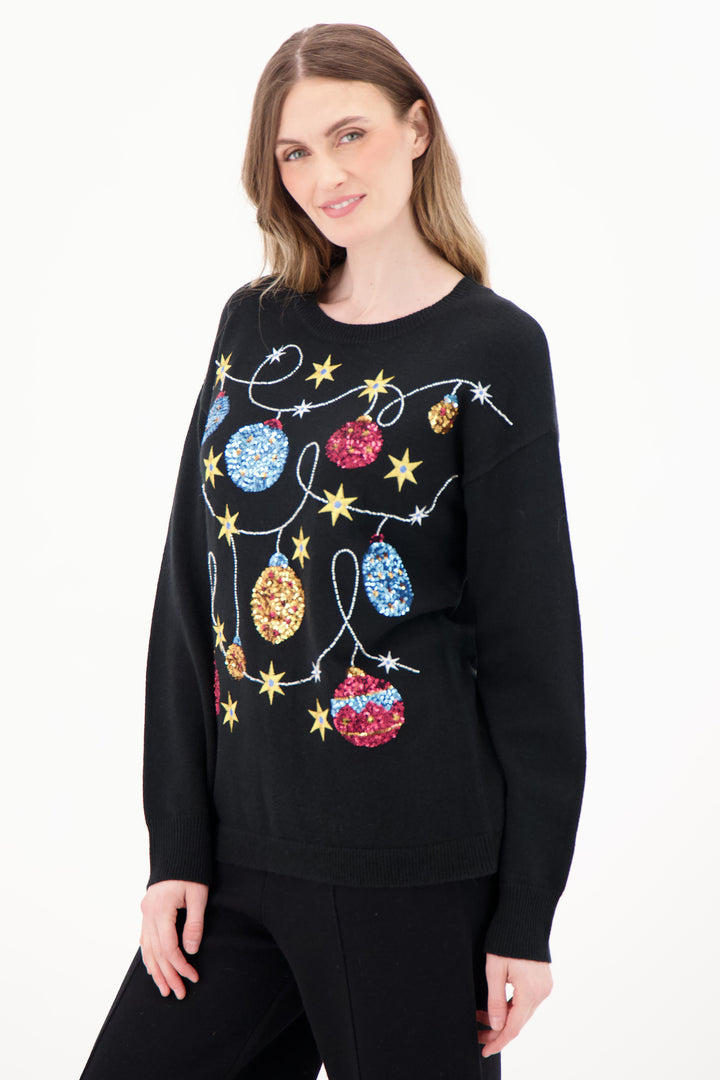 Woman wearing a black sweater with colorful Christmas-themed decorations on a white background