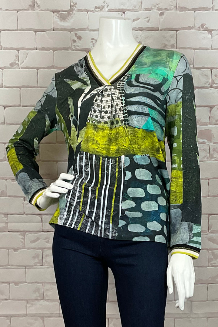 Dolcezza Fall 2024  This unique top features a vibrant abstract print displayed on both the front and back. With the pleated center fold detail below the neck and printed cuffs, you’ll be turning heads everywhere you go. 