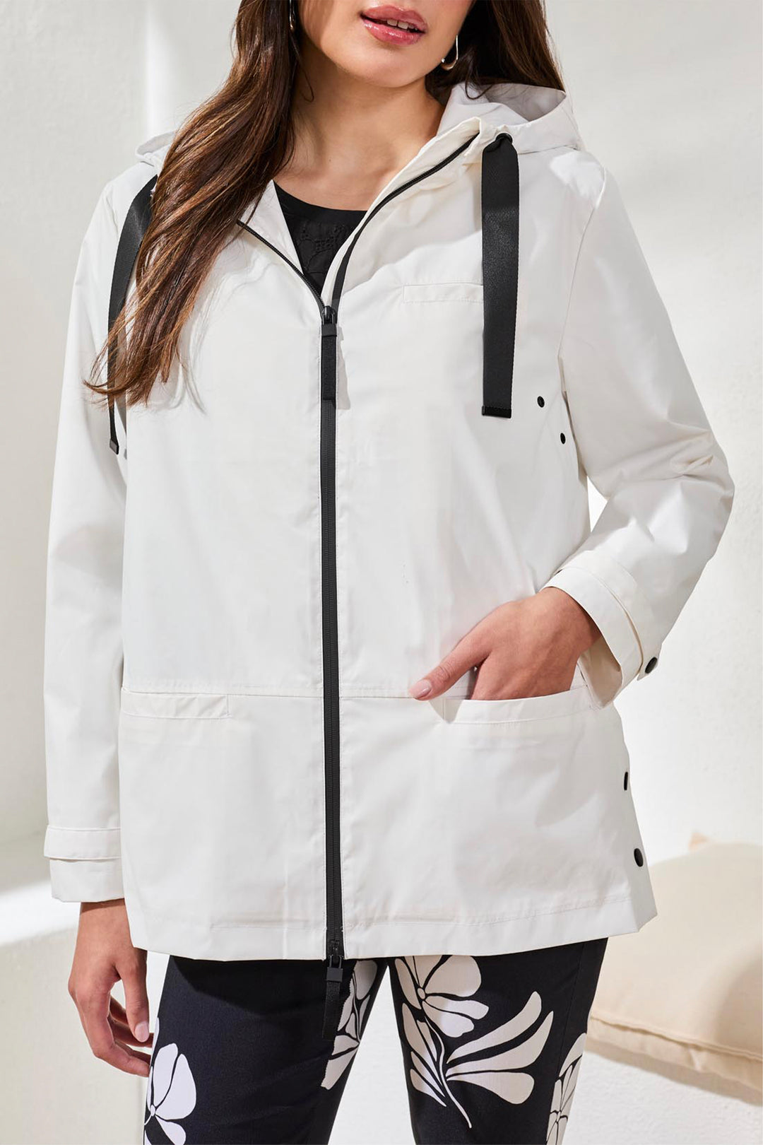 Woman wearing a white raincoat with black accents on a white background