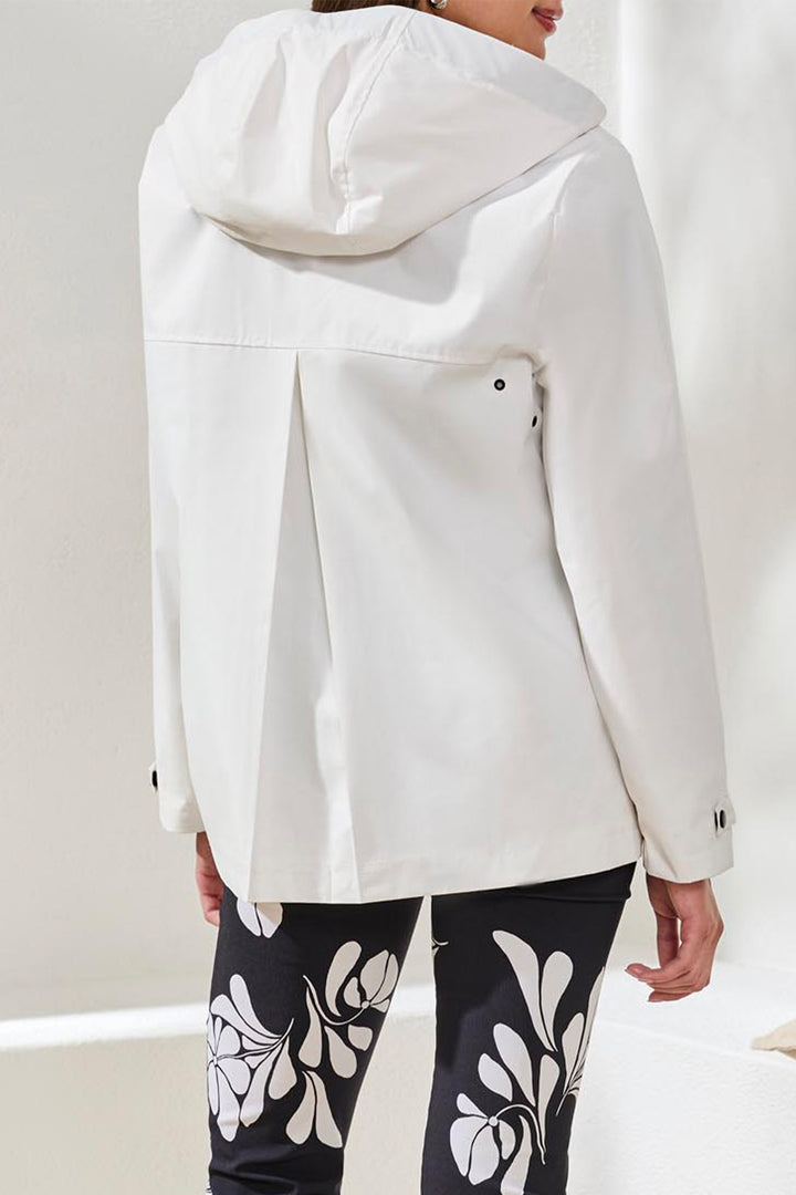 Person wearing a white coat and black leggings with floral patterns on a light background